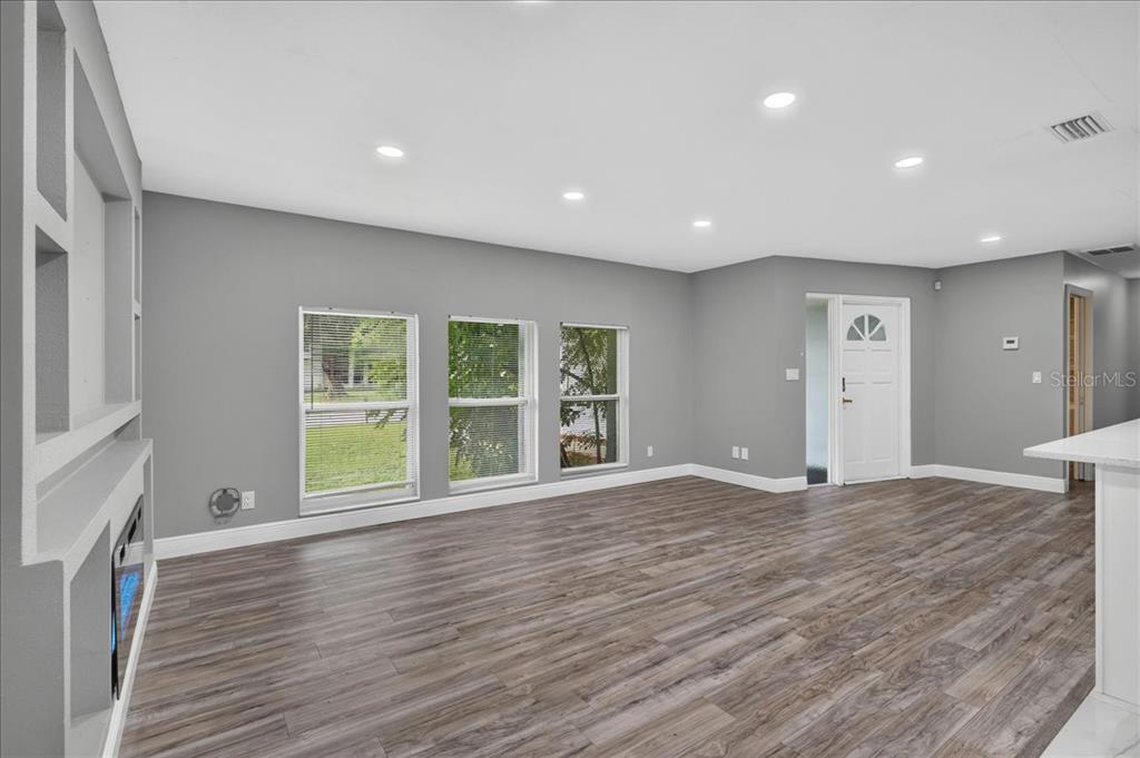 A living room features gray walls, recessed lighting, and wood-look flooring with a built-in fireplace — 2964 MEADOW OAK DRIVE S, CLEARWATER, FL