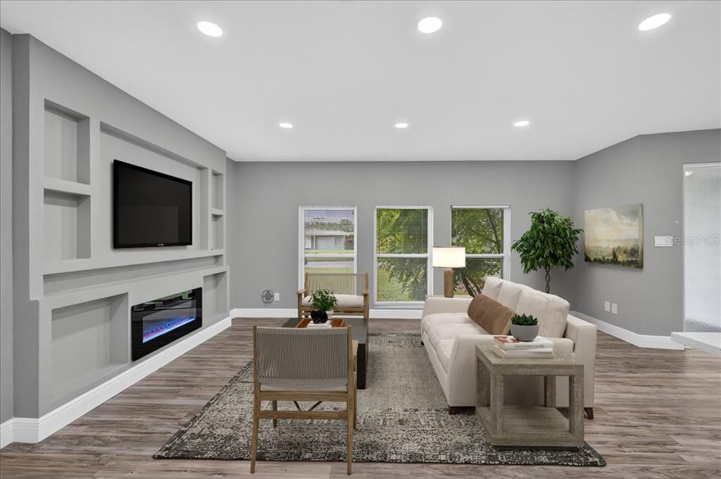 A living room features a built-in media wall with a fireplace, gray walls, and flooring — 2964 MEADOW OAK DRIVE S, CLEARWATER, FL