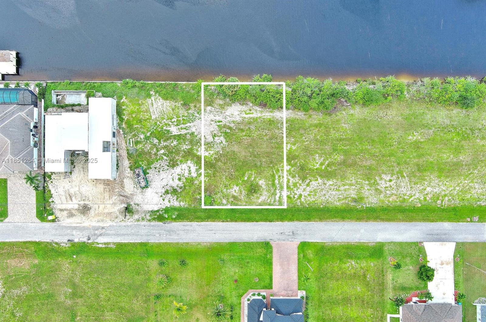 An aerial view shows a rectangular vacant lot bordering a canal — 1228 NW 34th Ave, Cape Coral FL 33993, CAPE CORAL, FL
