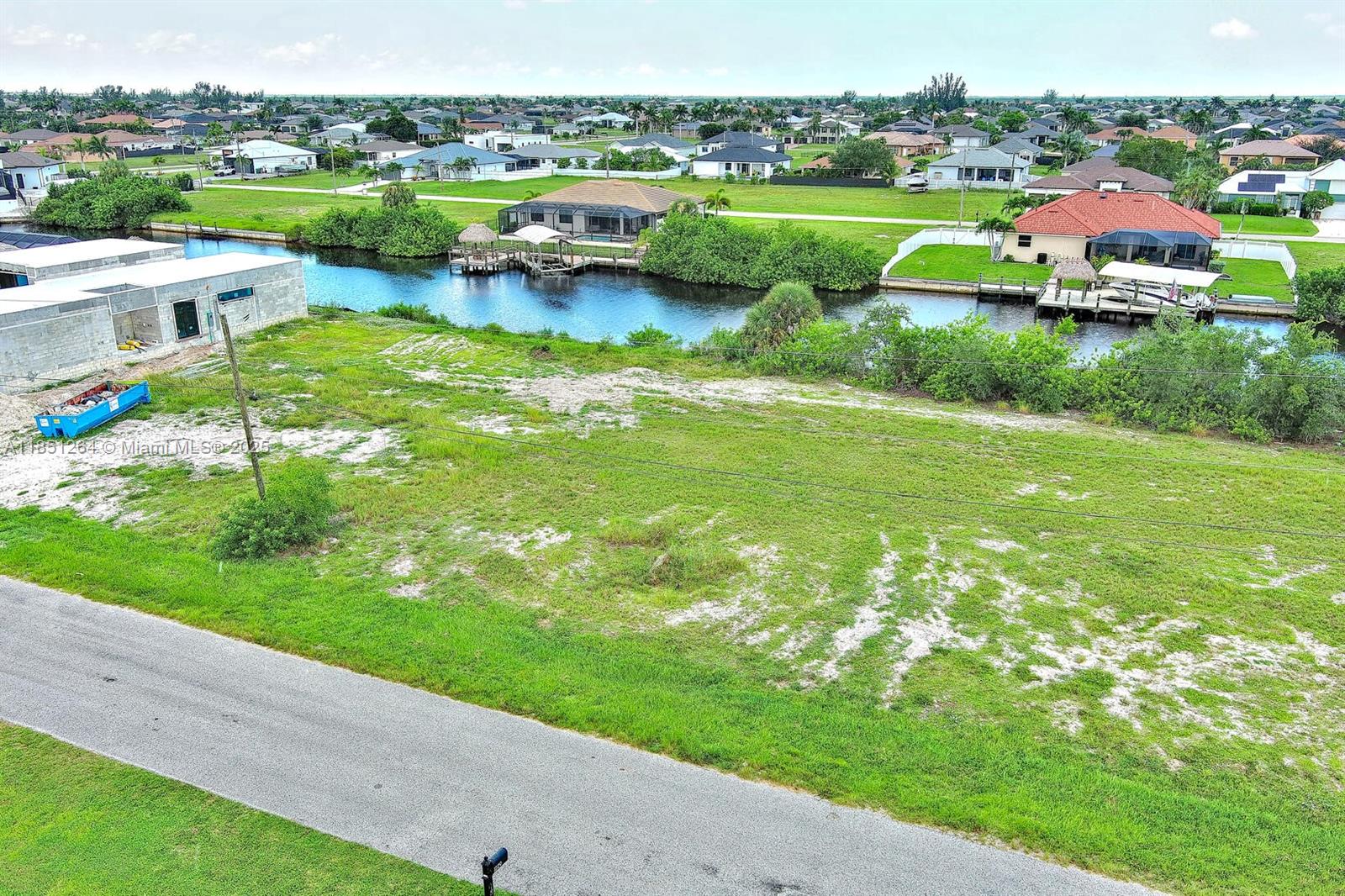 An elevated view shows a vacant grassy lot beside a canal and residential neighborhood — 1228 NW 34th Ave, Cape Coral FL 33993, CAPE CORAL, FL