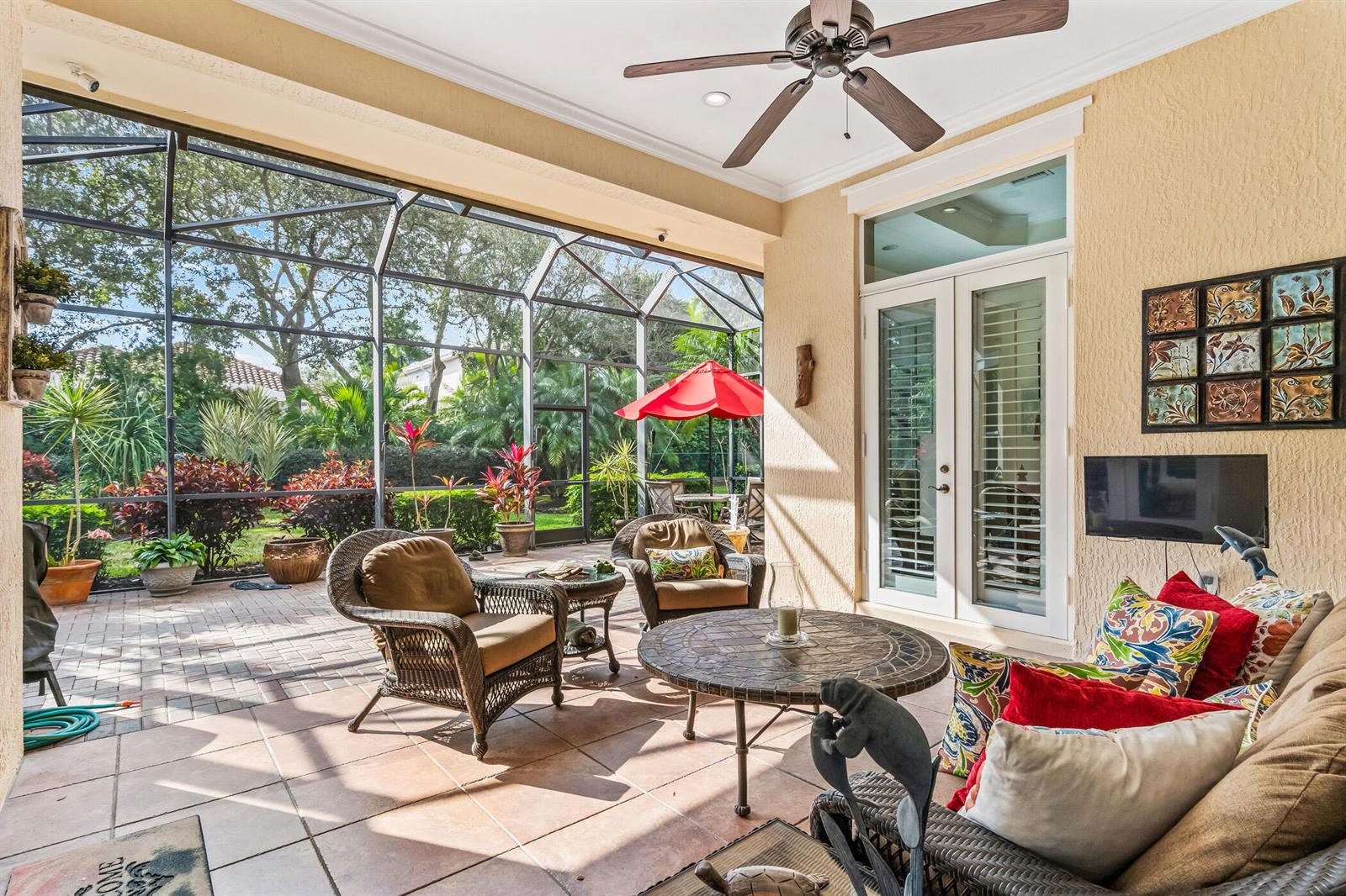 A screened-in patio features wicker furniture, a tiled floor, and a view of the backyard — 1209 River Wind Circle, Vero Beach FL 32967, VERO BEACH, FL