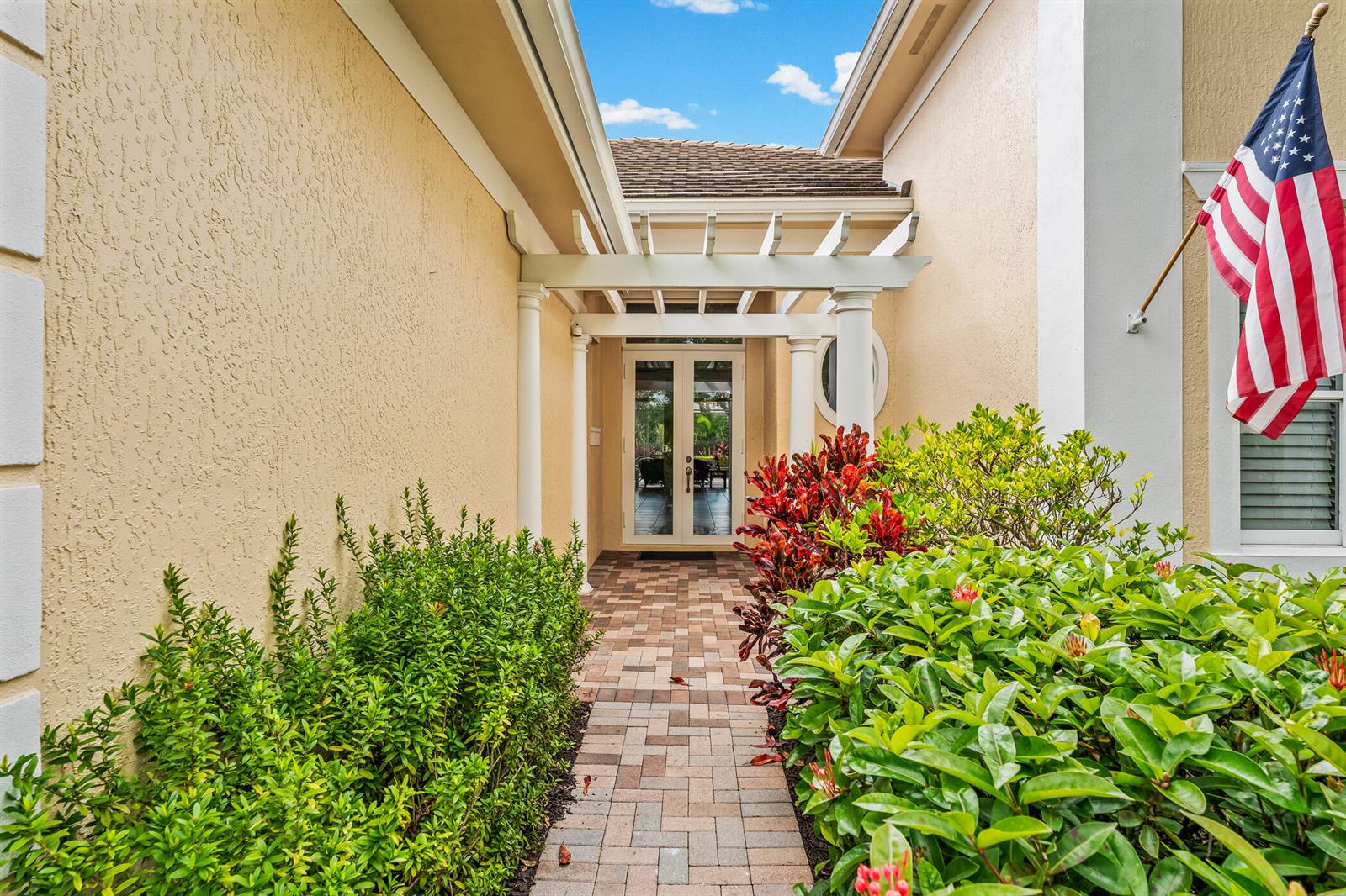 A paved walkway leads to a front entrance with a pergola and double glass doors — 1209 River Wind Circle, Vero Beach FL 32967, VERO BEACH, FL