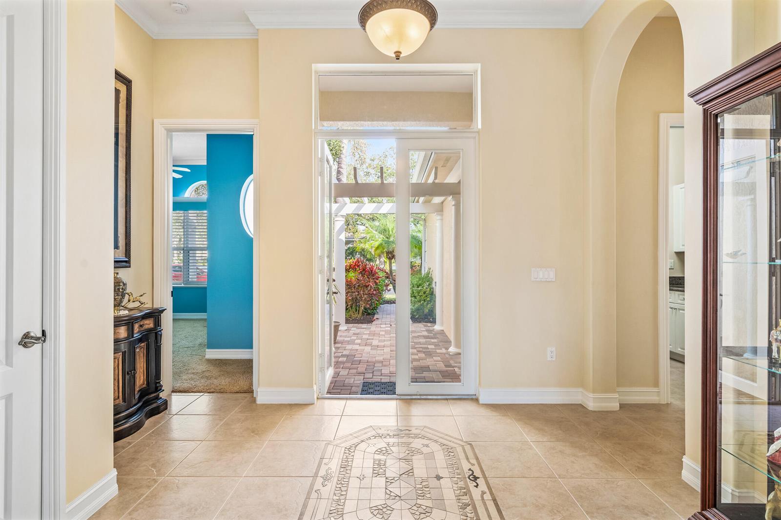 A tiled foyer features a central decorative inlay, a glass door, and a view outdoors — 1209 River Wind Circle, Vero Beach FL 32967, VERO BEACH, FL