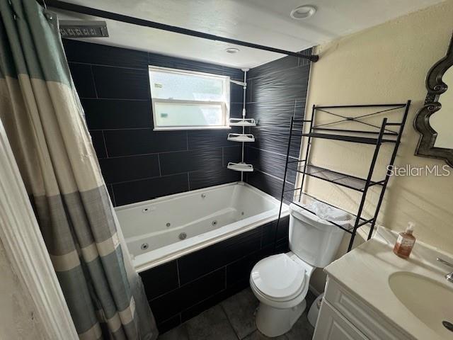 A bathroom features a jetted tub with black tile surround, a toilet, and a vanity — 7235 REDBUD COURT, NEW PORT RICHEY, FL