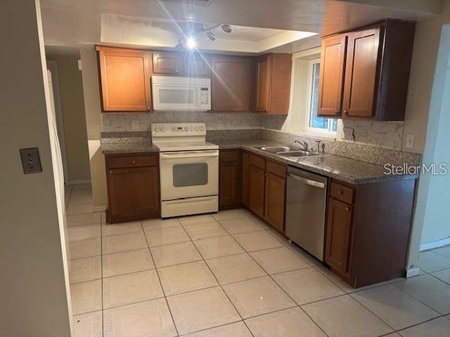 A kitchen features wood cabinets, granite countertops, white appliances, and light-colored tile flooring — 7235 REDBUD COURT, NEW PORT RICHEY, FL