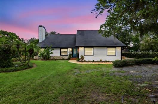 A single-story house with light siding, a dark roof, and a prominent chimney at sunset — 1637 GRAN VIADUCT, ORLANDO, FL