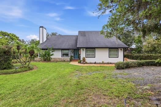 A white house with a dark roof and a tall chimney sits on a grassy lot — 1637 GRAN VIADUCT, ORLANDO, FL