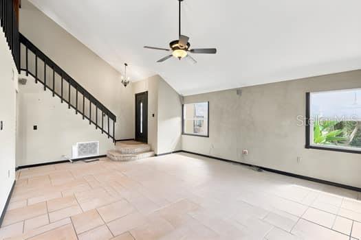 An open living area features light tile flooring, a vaulted ceiling, and a staircase — 1637 GRAN VIADUCT, ORLANDO, FL