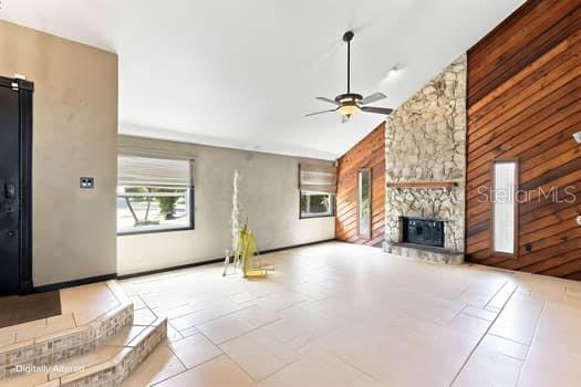 A living room features tile flooring, a stone fireplace, and wood-paneled walls under a vaulted ceiling — 1637 GRAN VIADUCT, ORLANDO, FL