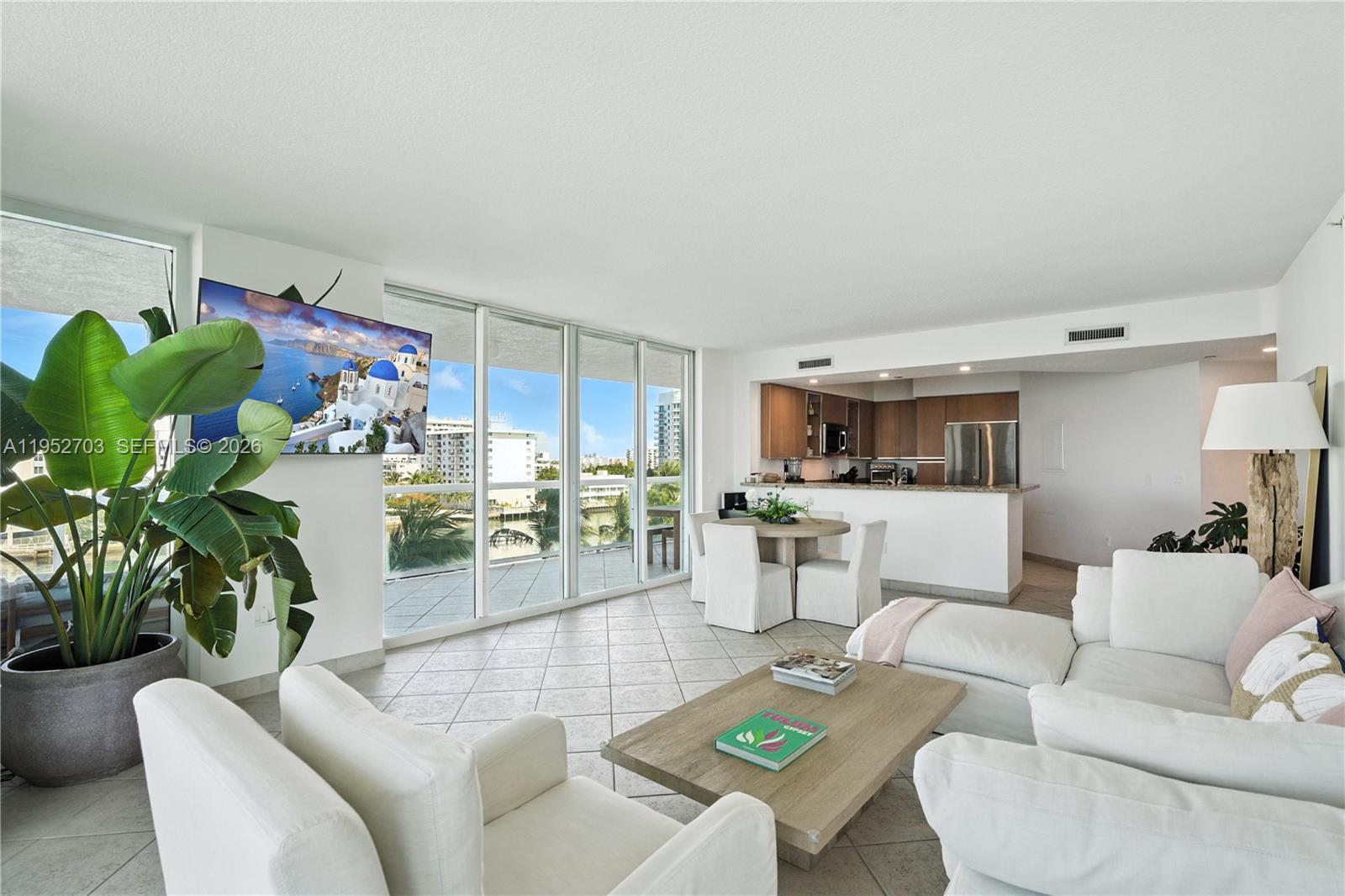 A bright living room features white furniture, tile floors, and a kitchen with wooden cabinets — 10 Venetian Way # 604, Miami Beach FL 33139, MIAMI BEACH, FL