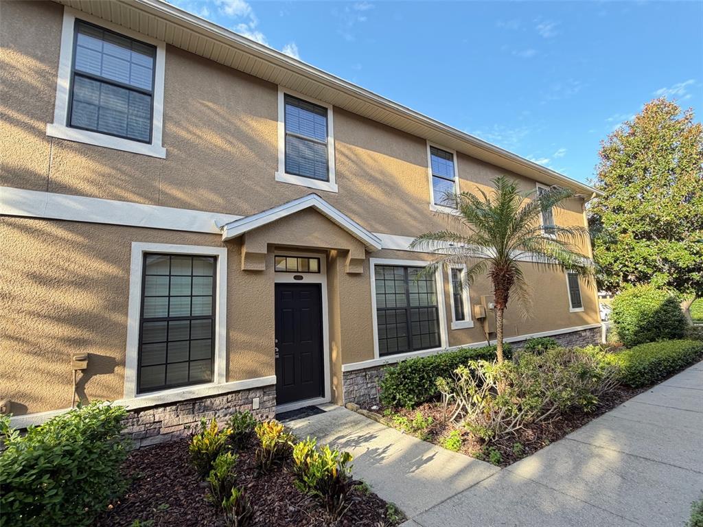 A two-story tan stucco building features a dark front door and stone veneer base — 5722 KINGLETHILL DRIVE, LITHIA, FL