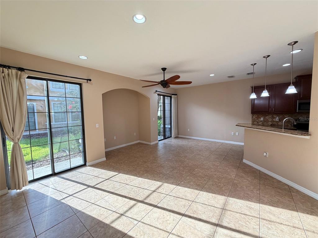 An open-concept living area features tile flooring, a ceiling fan, and an adjacent kitchen — 5722 KINGLETHILL DRIVE, LITHIA, FL