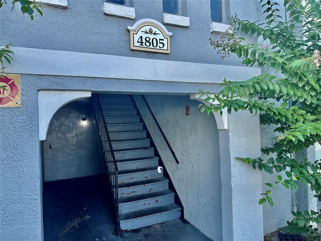 An exterior view of a building entrance featuring a staircase leading to an upper level — 4805 S TEXAS AVENUE UNIT 4805C, ORLANDO, FL