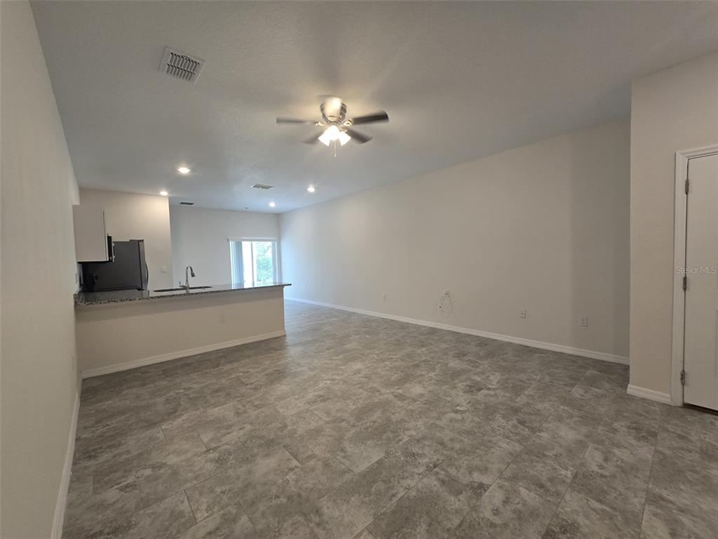 An open-concept living area features gray tile flooring, a ceiling fan, and a kitchen island — 546 IMPERIAL PL UNIT 548, KISSIMMEE, FL