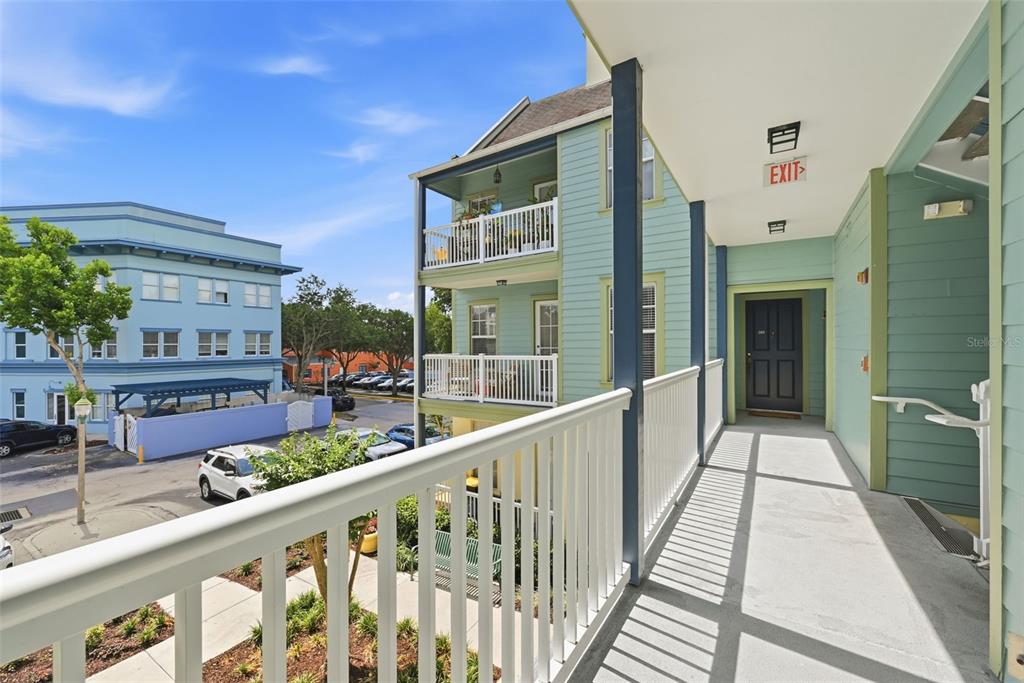 An exterior view of a building balcony with white railings, a dark door, and siding — 611 CAMPUS STREET UNIT 280, CELEBRATION, FL