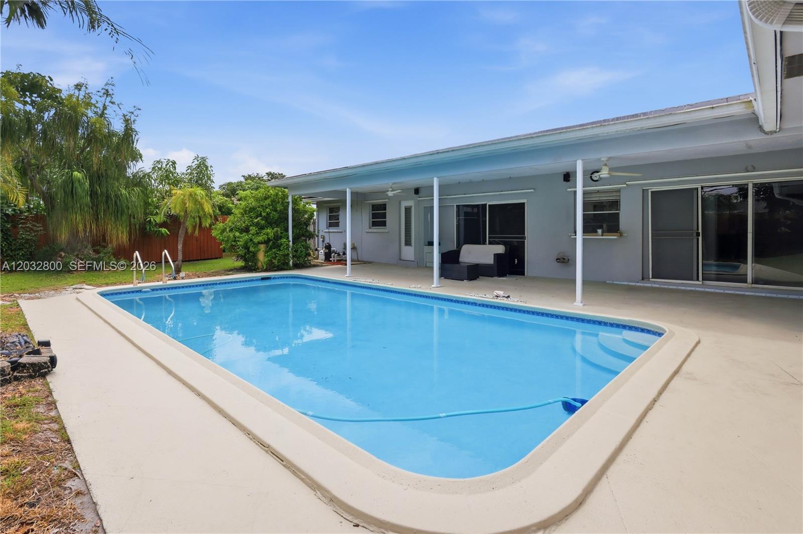 A rectangular swimming pool sits on a concrete patio beside a single-story house — 7421 NW 14th St, Plantation FL 33313, PLANTATION, FL