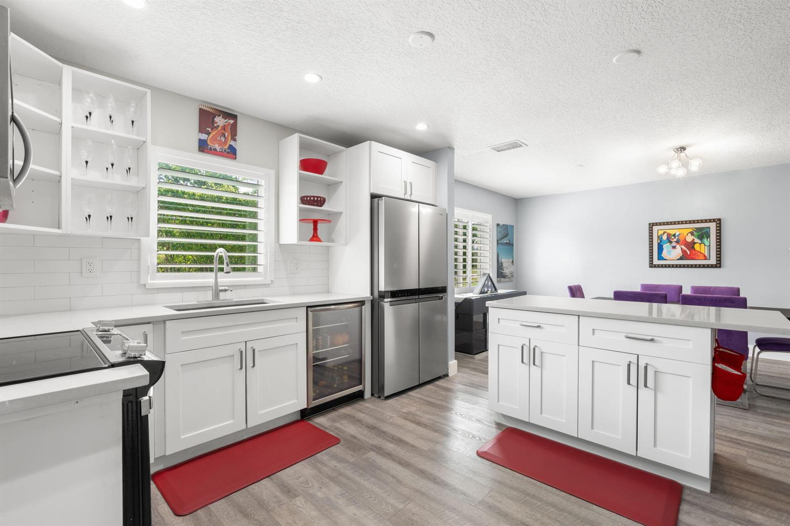 A modern kitchen features white cabinetry, stainless steel appliances, and a central island with seating — 13491 Via Vesta, Delray Beach FL 33484, DELRAY BEACH, FL