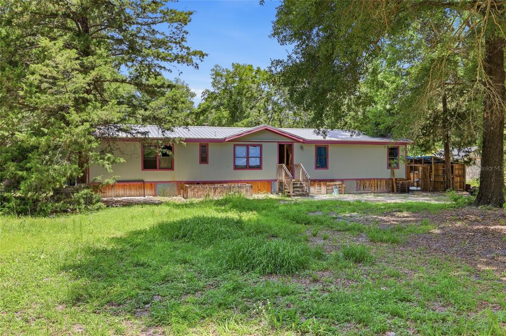 A single-story manufactured home with light-colored siding and red trim sits on a grassy lot — 12725 212TH TERRACE, O'BRIEN, FL