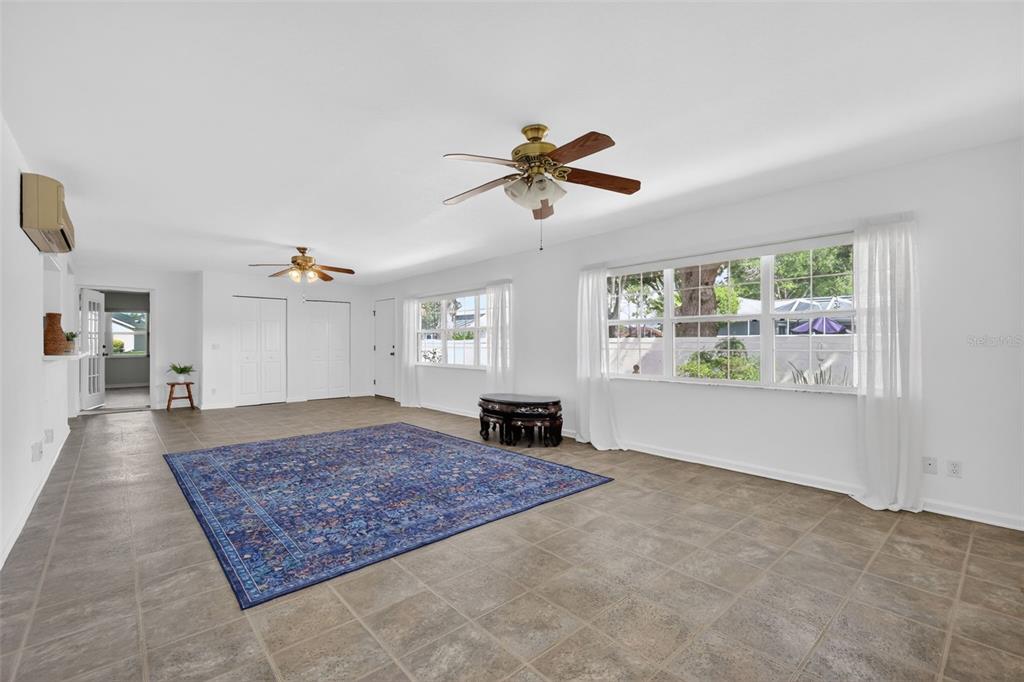 A bright living room features tile flooring, two ceiling fans, and large windows with curtains — 17808 SE 115TH COURT, SUMMERFIELD, FL