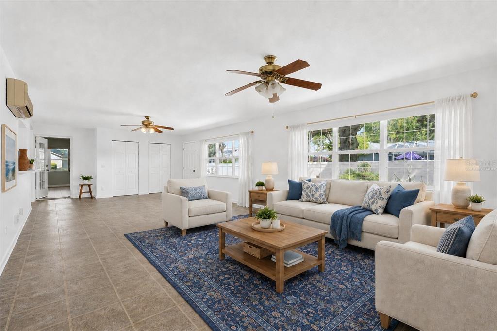 A bright living room features tile floors, two ceiling fans, and a large area rug — 17808 SE 115TH COURT, SUMMERFIELD, FL