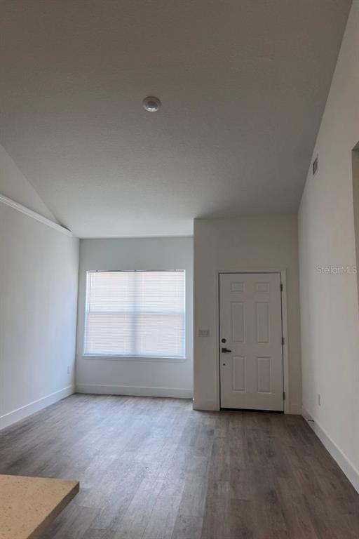 An empty room with light-colored walls, wood-look flooring, a window with blinds, and a door — 1786 CORIANDER DRIVE, POINCIANA, FL