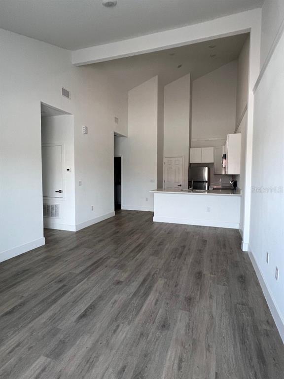 An open-concept living area features high ceilings, white walls, and gray wood-look flooring — 1786 CORIANDER DRIVE, POINCIANA, FL
