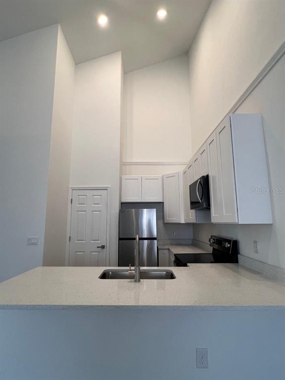 A kitchen features white cabinetry, stainless steel appliances, and a quartz countertop with a sink — 1786 CORIANDER DRIVE, POINCIANA, FL