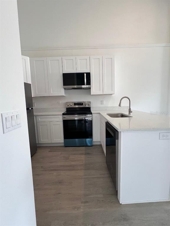 A kitchen features white cabinets, stainless steel appliances, and light-colored countertops — 1786 CORIANDER DRIVE, POINCIANA, FL