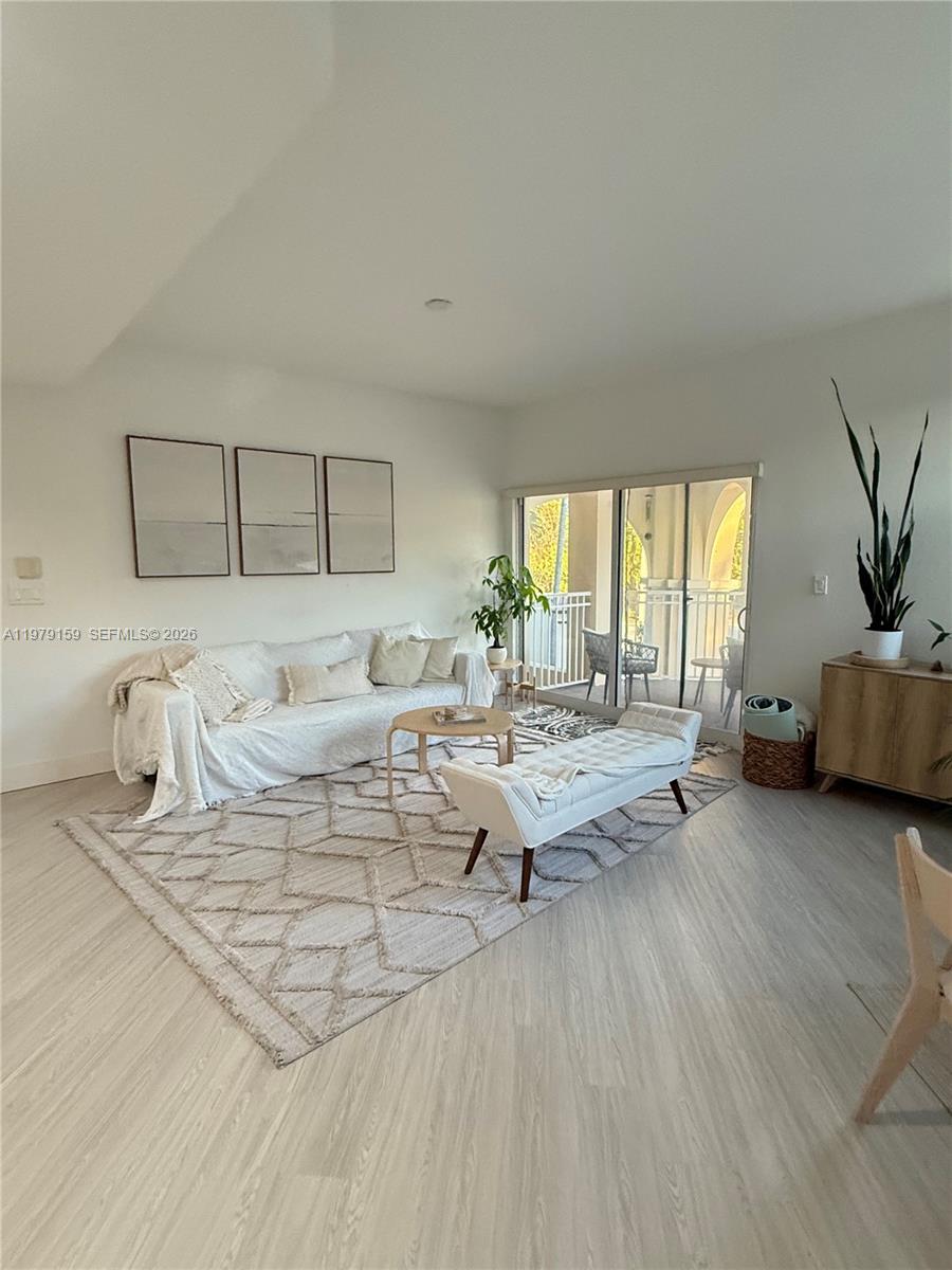 A living room features a white sofa, a bench, a patterned rug, and sliding glass doors — 8999 NW 107th Ct # 1, Doral FL 33178, DORAL, FL