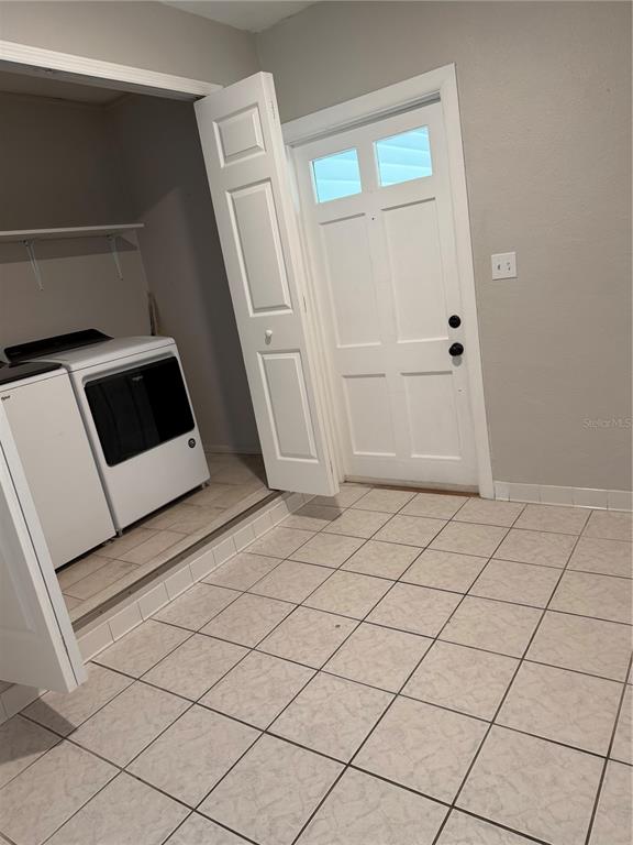 A laundry room features a white washer and dryer set, tiled flooring, and an exterior door — 2419 WELLS AVENUE, SARASOTA, FL
