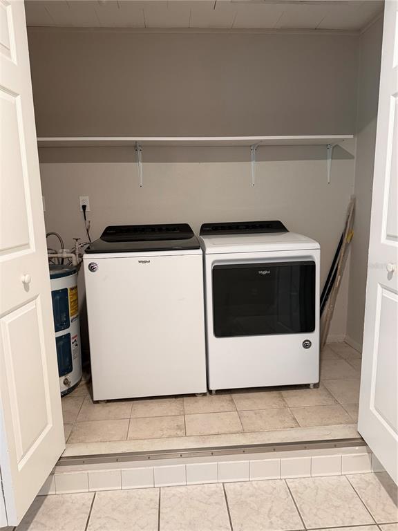 A laundry closet contains a white washer, dryer, and water heater under a wall shelf — 2419 WELLS AVENUE, SARASOTA, FL