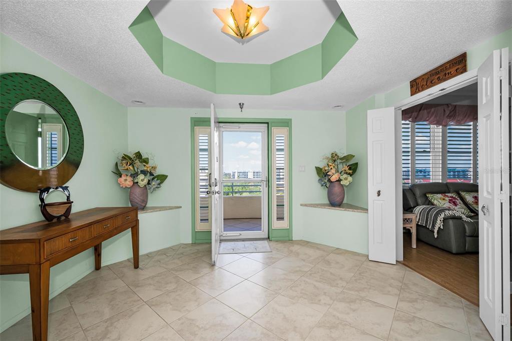 An entryway with light green walls, tile flooring, a tray ceiling, and a glass door — 7882 SAILBOAT KEY BOULEVARD S UNIT 605, SOUTH PASADENA, FL