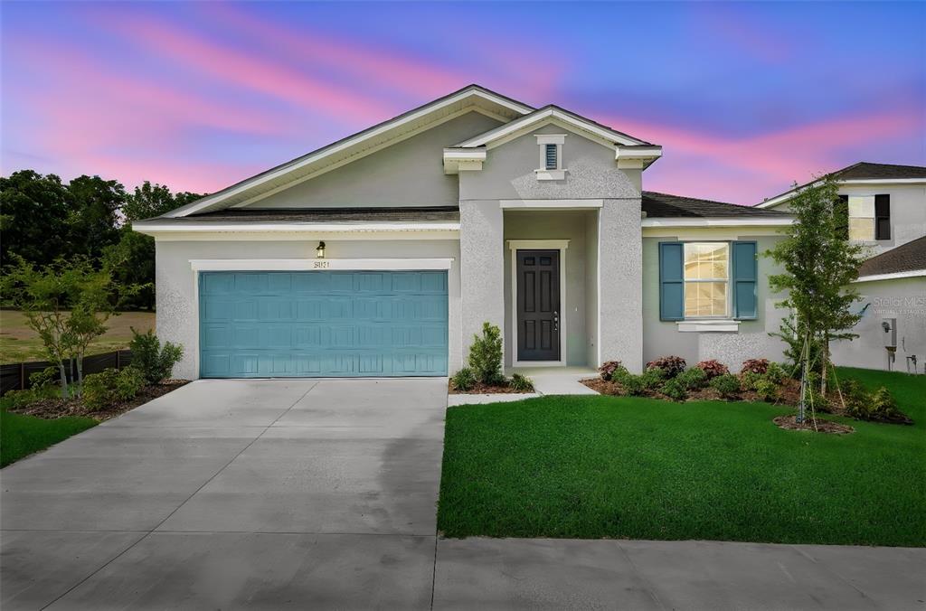 A single-story house with a blue garage door, gray stucco exterior, and a front lawn — 35151 TUSCAN HILL ROAD, DADE CITY, FL