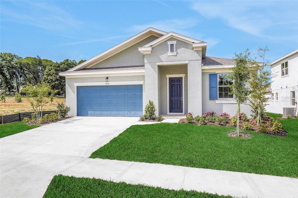A single-story house with a blue garage door, blue front door, and a concrete driveway — 35151 TUSCAN HILL ROAD, DADE CITY, FL
