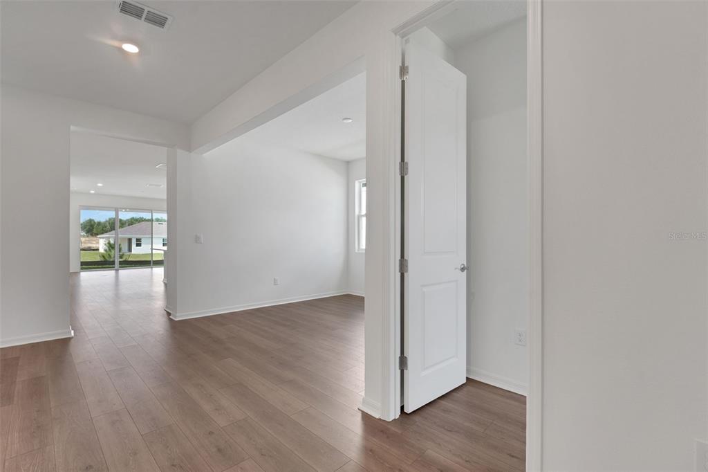 An interior view shows a hallway with wood-look flooring leading to an open living area — 35151 TUSCAN HILL ROAD, DADE CITY, FL