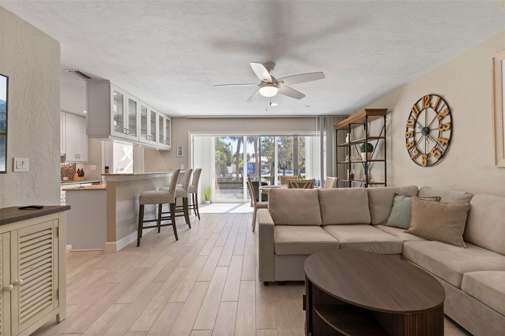 A living room and kitchen area with a sectional sofa, breakfast bar, and sliding doors — 137 AVENIDA MESSINA UNIT 1, SARASOTA, FL