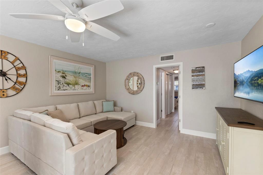 A living room features a sectional sofa, a round coffee table, and a wall-mounted television — 137 AVENIDA MESSINA UNIT 1, SARASOTA, FL