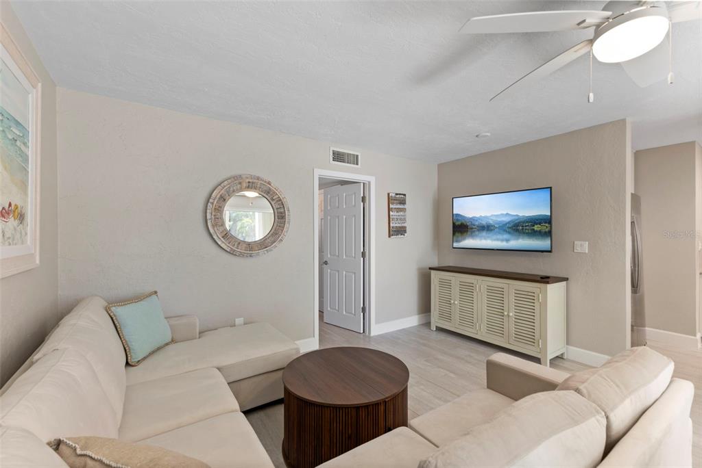 A living room features a sectional sofa, a round coffee table, and a wall-mounted television — 137 AVENIDA MESSINA UNIT 1, SARASOTA, FL