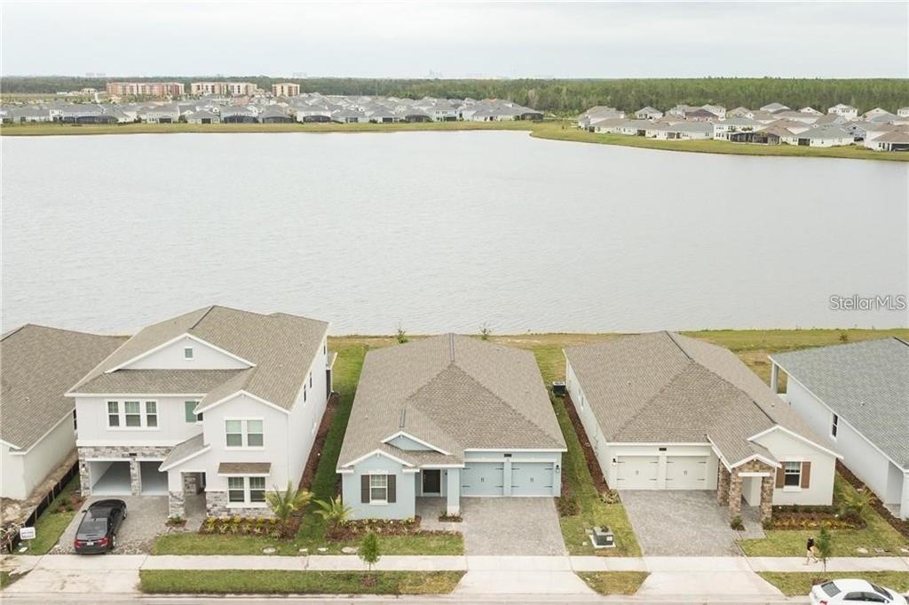 An aerial view shows three suburban houses situated along the edge of a large lake — 4625 RHYTHM ROAD, KISSIMMEE, FL