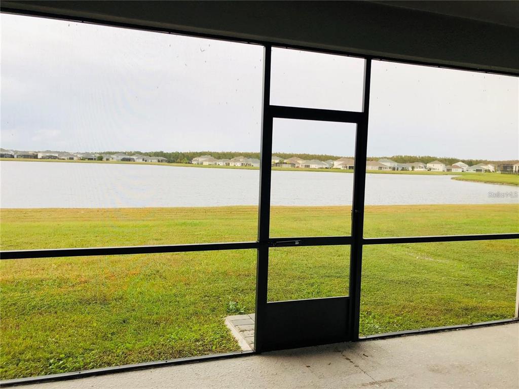 A view of a lake and neighborhood from a screened-in patio — 4625 RHYTHM ROAD, KISSIMMEE, FL