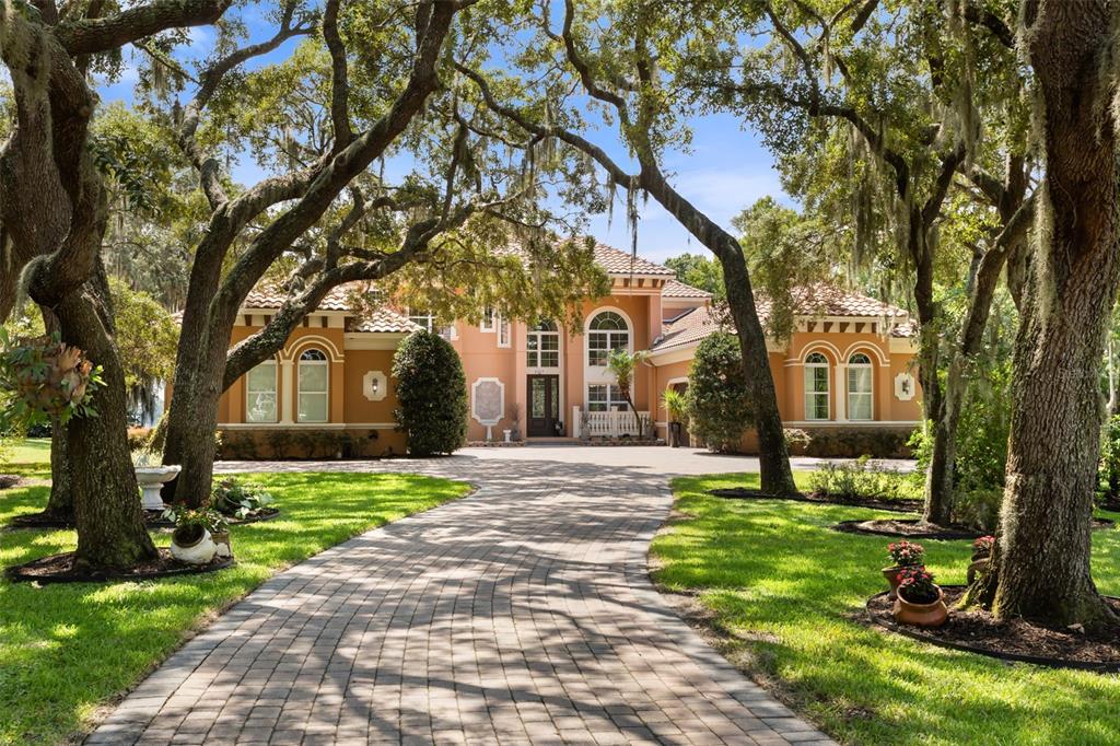 A two-story stucco house with a tile roof and a paved driveway framed by trees — 2117 STURBRIDGE COURT, WINTER SPRINGS, FL