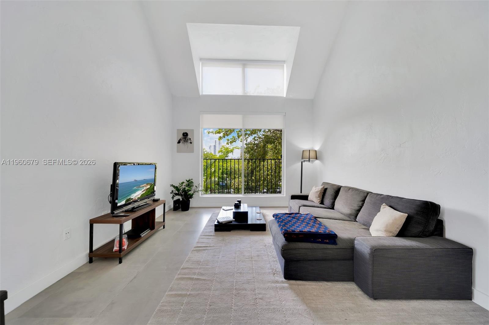 A living room features a vaulted ceiling, a gray sectional sofa, and a balcony view — 6900 N Kendall Dr # A303, Pinecrest FL 33156, PINECREST, FL