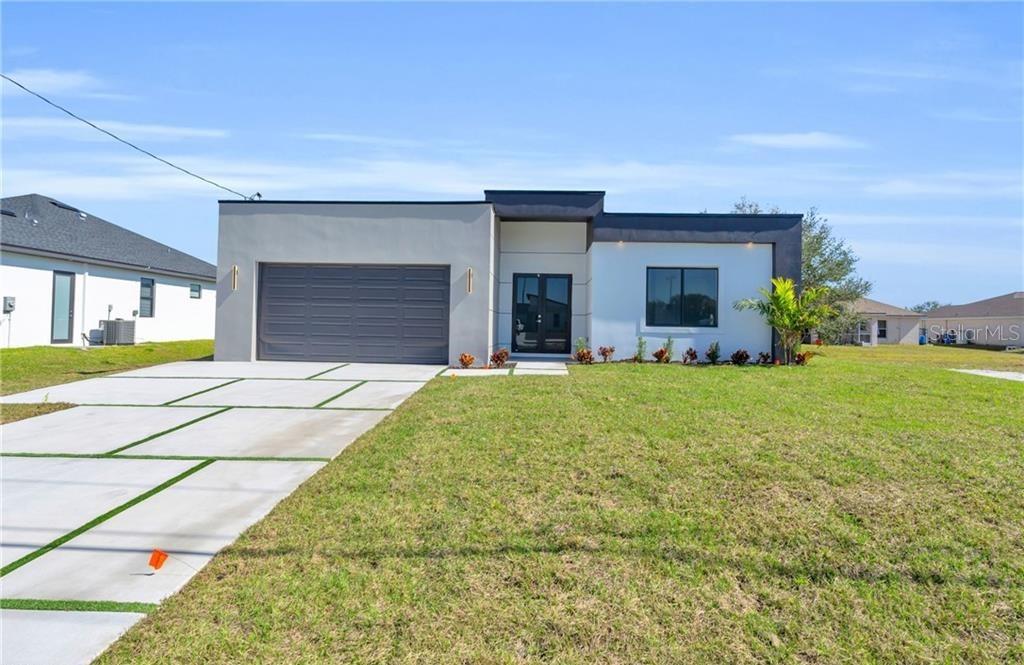 A modern single-story house with a gray garage, white facade, and a concrete driveway — 3617 NW 38TH TERRACE, CAPE CORAL, FL