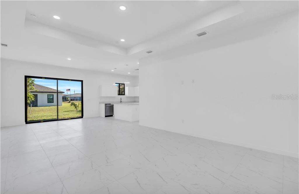An open-concept living area with white tile floors, recessed lighting, and a view of the backyard — 3617 NW 38TH TERRACE, CAPE CORAL, FL
