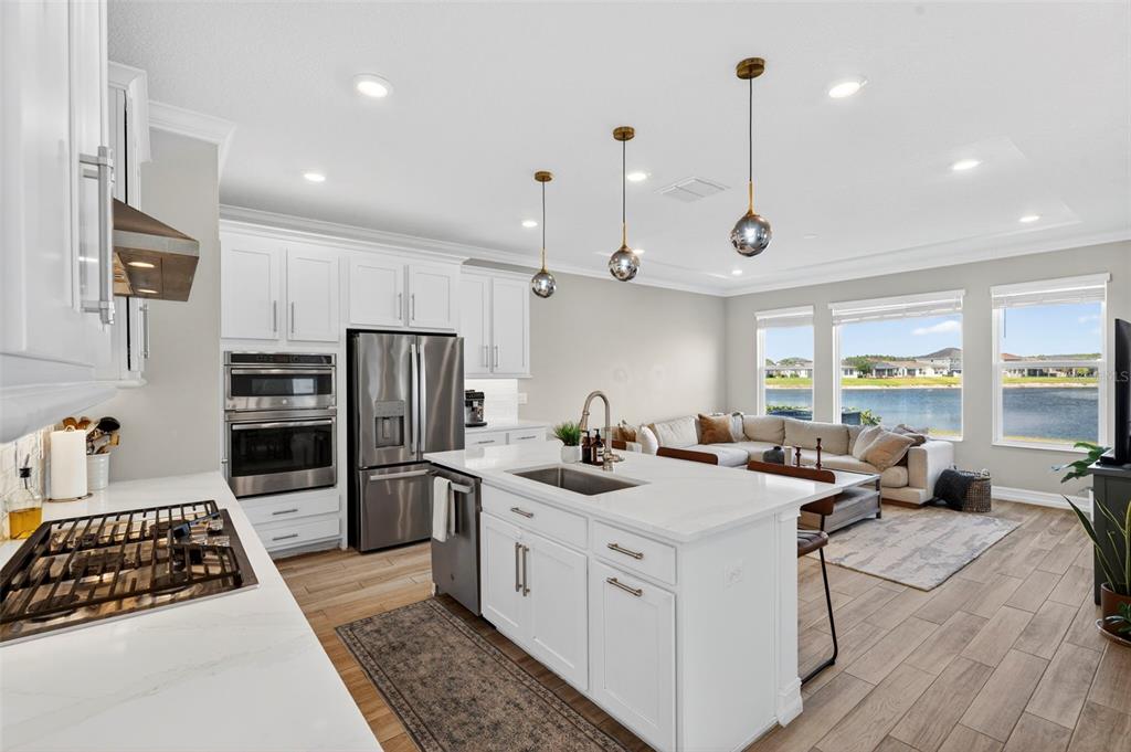 A modern kitchen with white cabinets and a center island overlooks a living area — 4588 SAN MARTINO DRIVE, WESLEY CHAPEL, FL