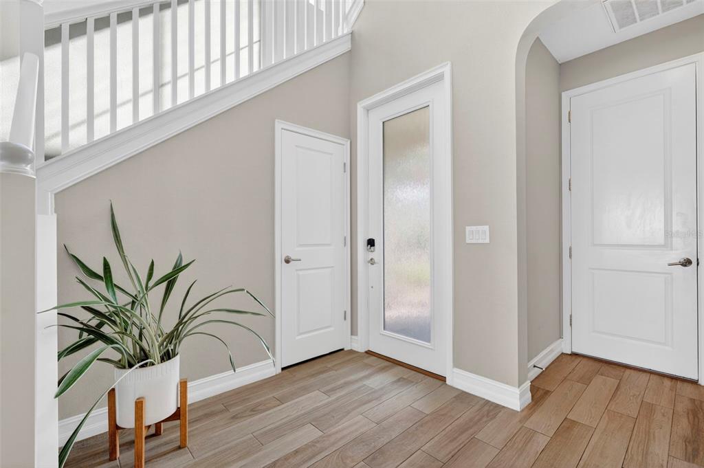 An entryway features wood-look tile flooring, a staircase with white railings, and three white doors — 4588 SAN MARTINO DRIVE, WESLEY CHAPEL, FL