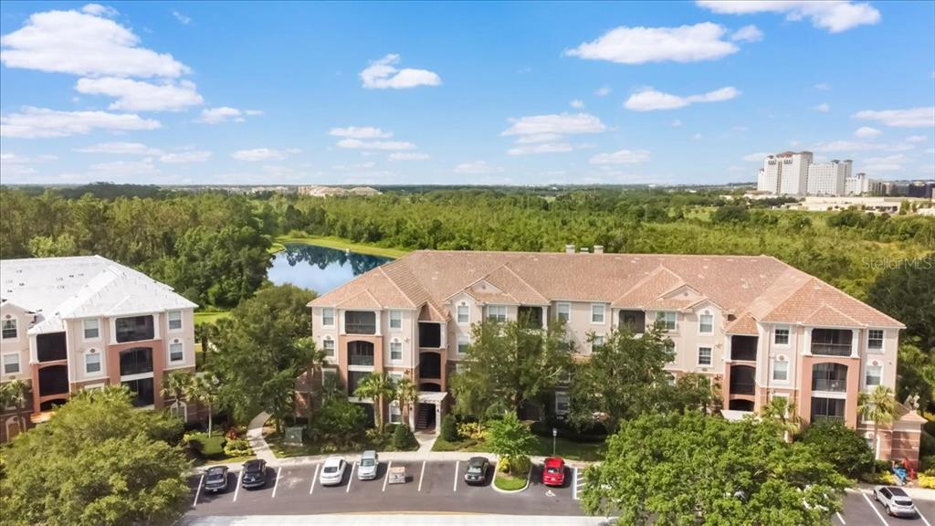An aerial view of a multi-story apartment building with a parking lot and a pond — 8304 PORTOFINO DRIVE UNIT 103, DAVENPORT, FL