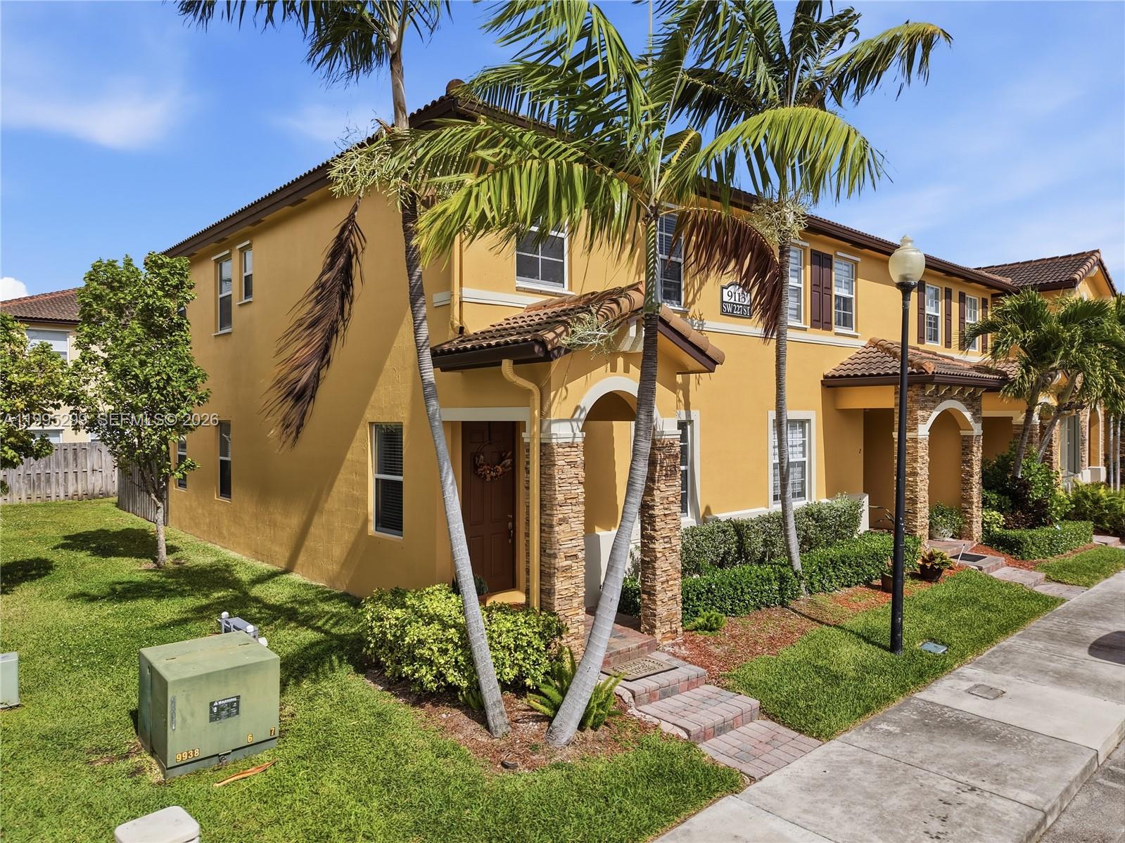 A two-story yellow stucco townhouse features a stone-accented entryway and palm trees in front — 9113 SW 227th St # 1, Cutler Bay FL 33190, CUTLER BAY, FL