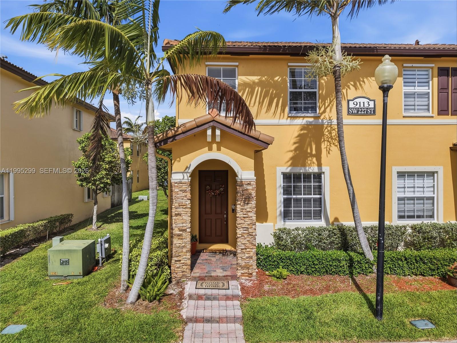 A two-story yellow stucco house features a stone-accented entryway and a brick walkway — 9113 SW 227th St # 1, Cutler Bay FL 33190, CUTLER BAY, FL