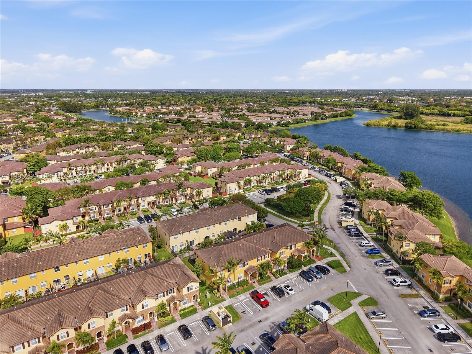 An aerial view shows a residential complex with yellow townhouses, parking lots, and a lake — 9113 SW 227th St # 1, Cutler Bay FL 33190, CUTLER BAY, FL